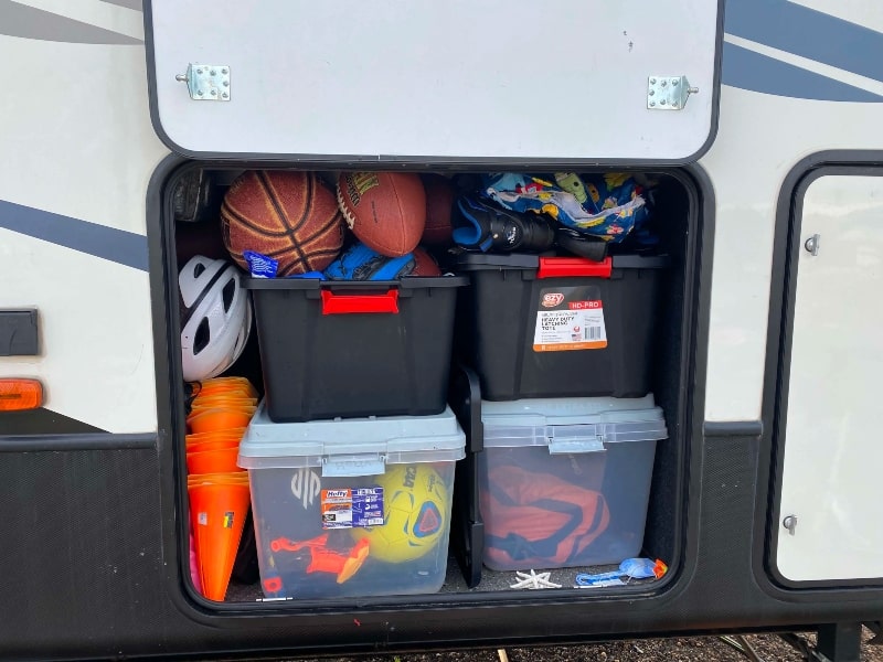 RV exterior storage compartment with plastic storage containers inside